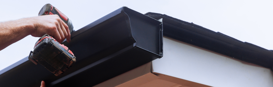 roofing contractor installing metal gutter system on residential home