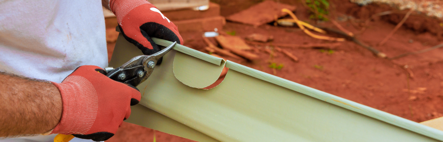 technician cutting aluminum gutter section during installation