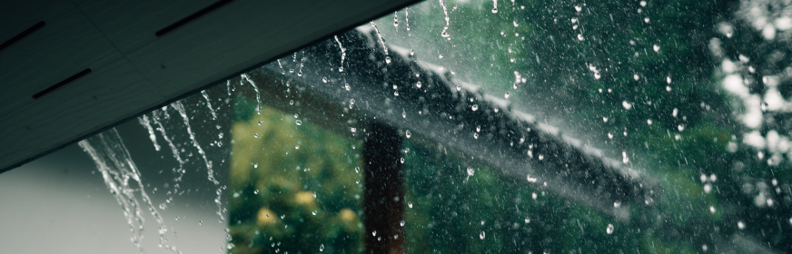 rainwater flowing through roof gutter system during storm